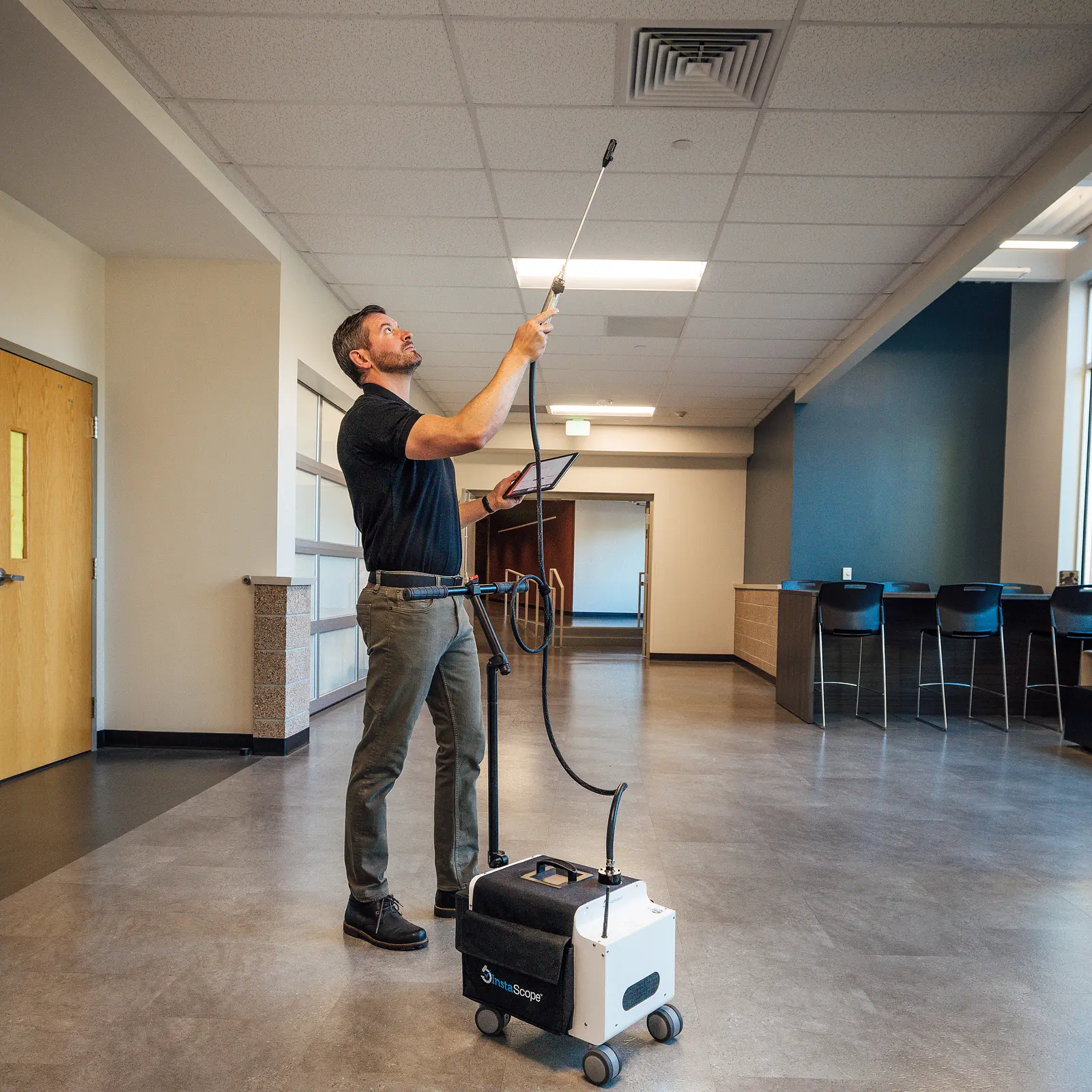 Technician using ceiling-mounted environmental testing equipment during an on-site inspection